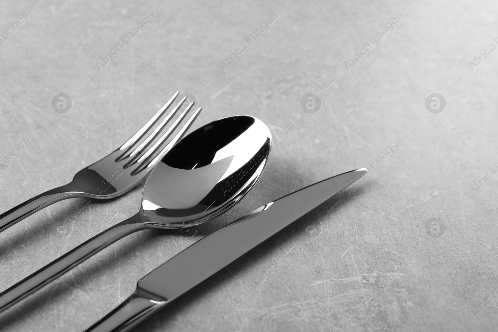 Photo of Stylish silver cutlery set on grey table, closeup. Space for text