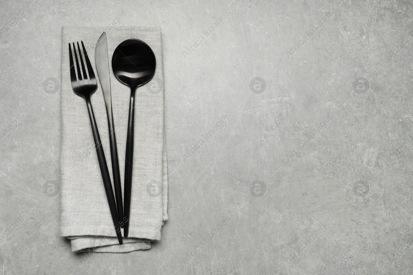 Photo of Stylish cutlery and napkin on grey table, top view. Space for text