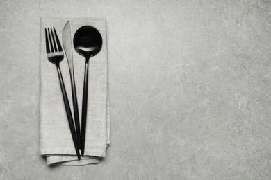 Photo of Stylish cutlery and napkin on grey table, top view. Space for text