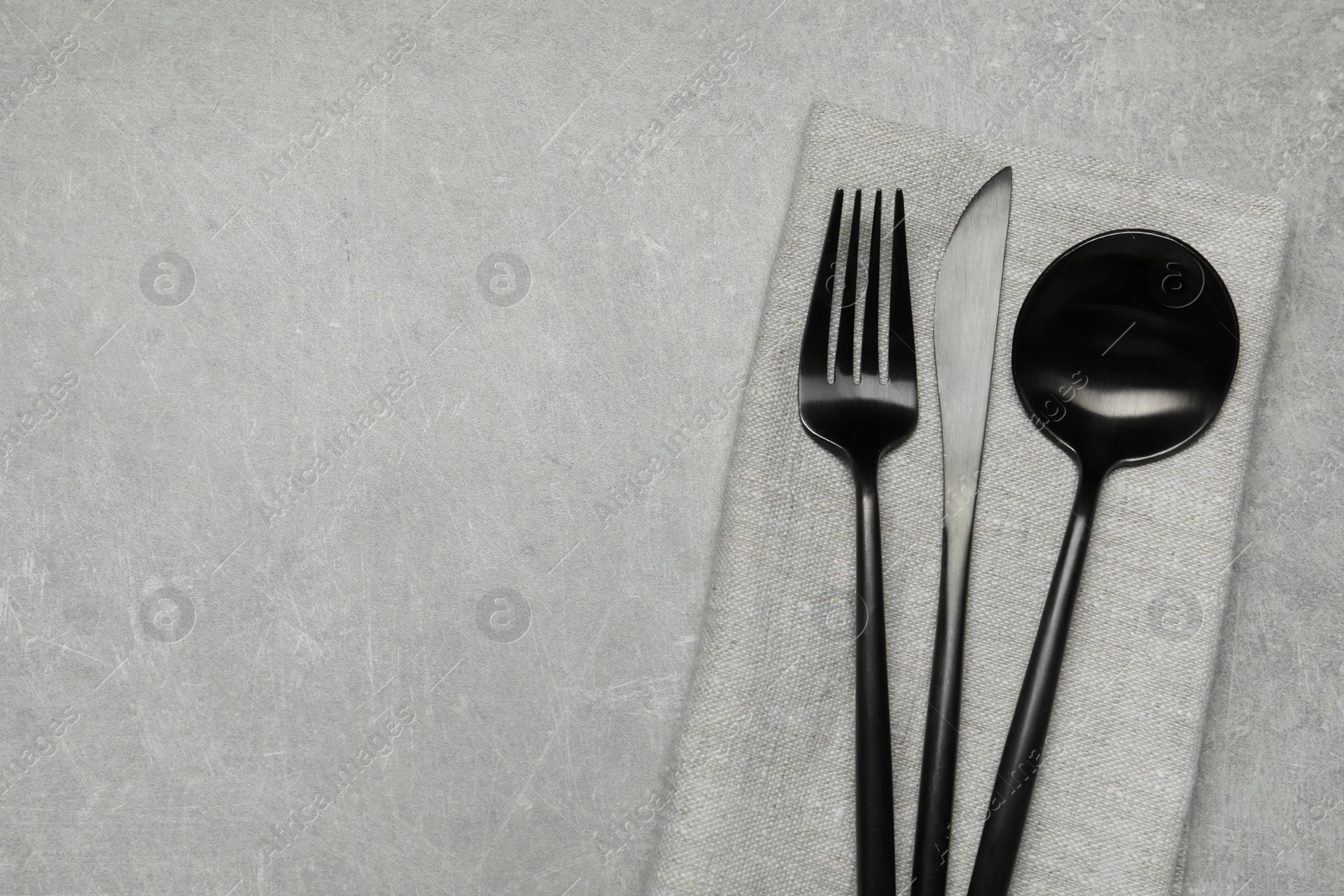 Photo of Stylish cutlery and napkin on grey table, top view. Space for text