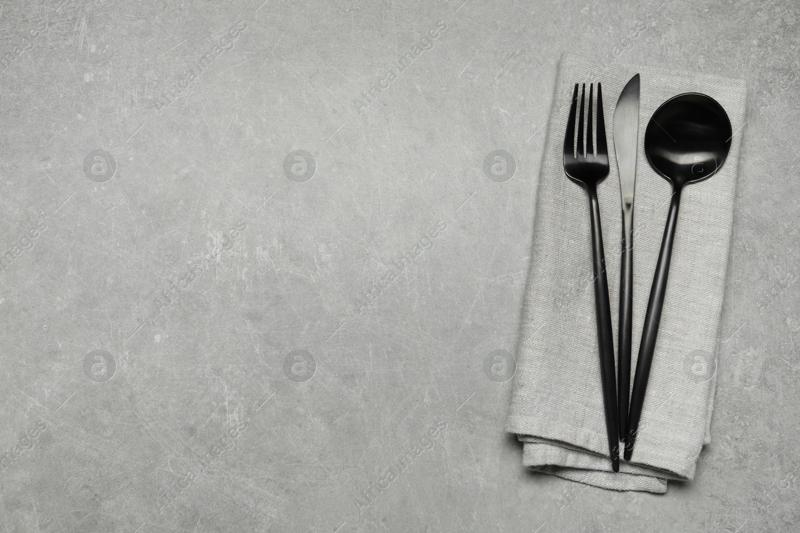 Photo of Stylish cutlery and napkin on grey table, top view. Space for text