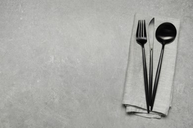 Stylish cutlery and napkin on grey table, top view. Space for text