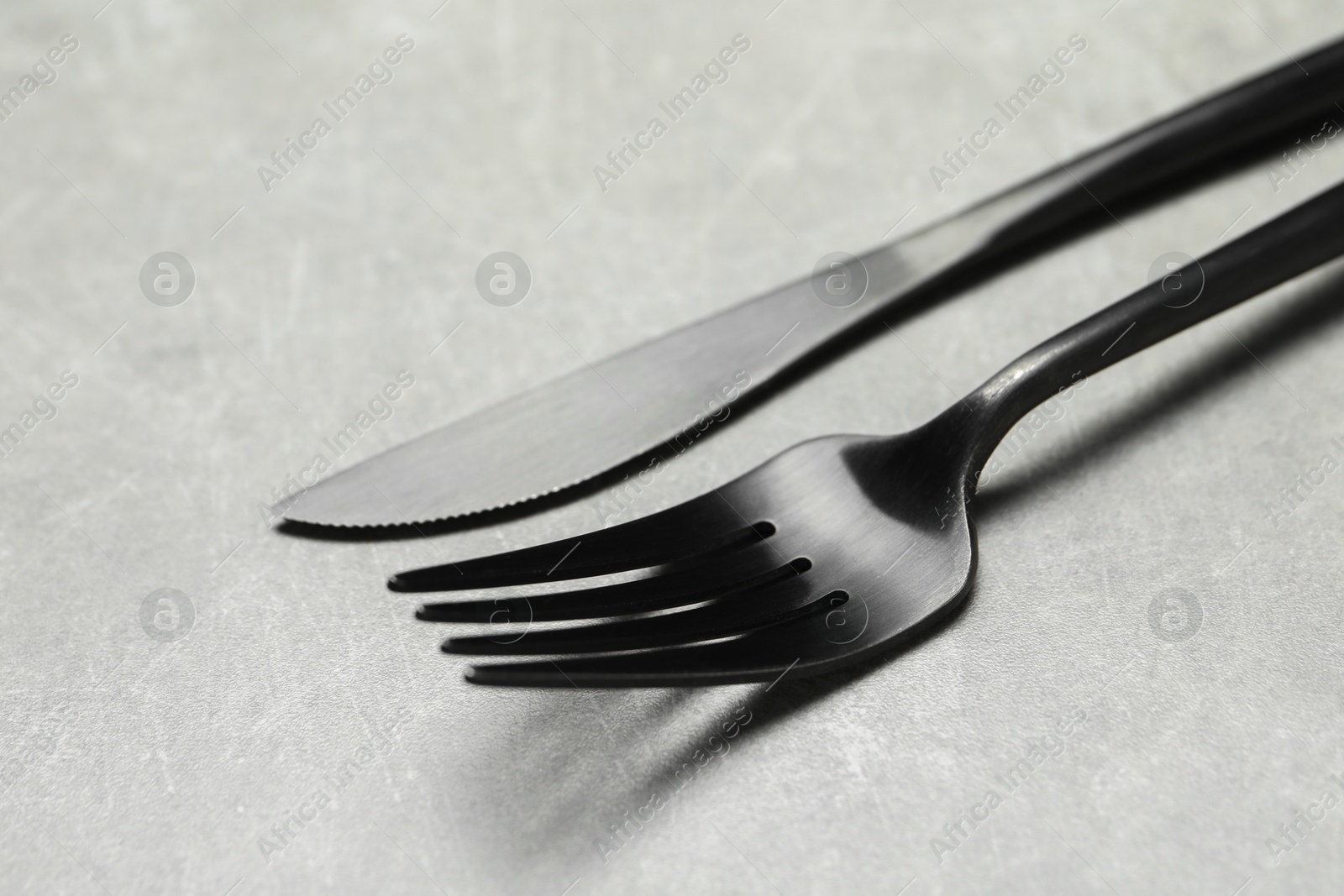 Photo of Stylish cutlery. Fork and knife on grey table, closeup