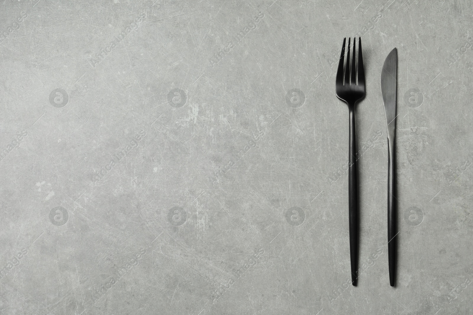 Photo of Stylish cutlery on grey table, top view. Space for text