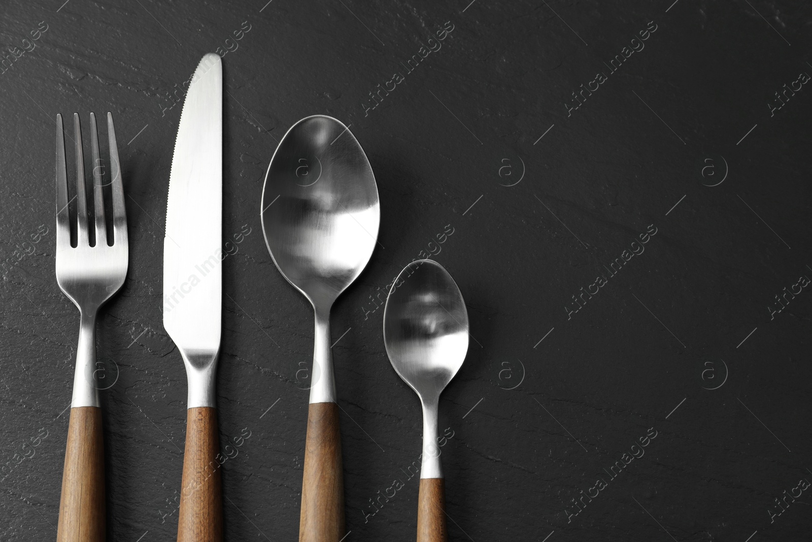 Photo of Stylish cutlery on black table, flat lay. Space for text