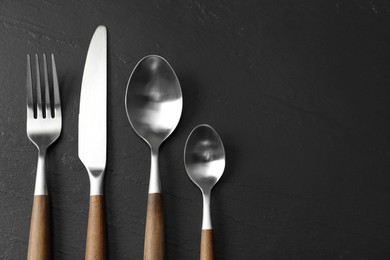 Photo of Stylish cutlery on black table, flat lay. Space for text