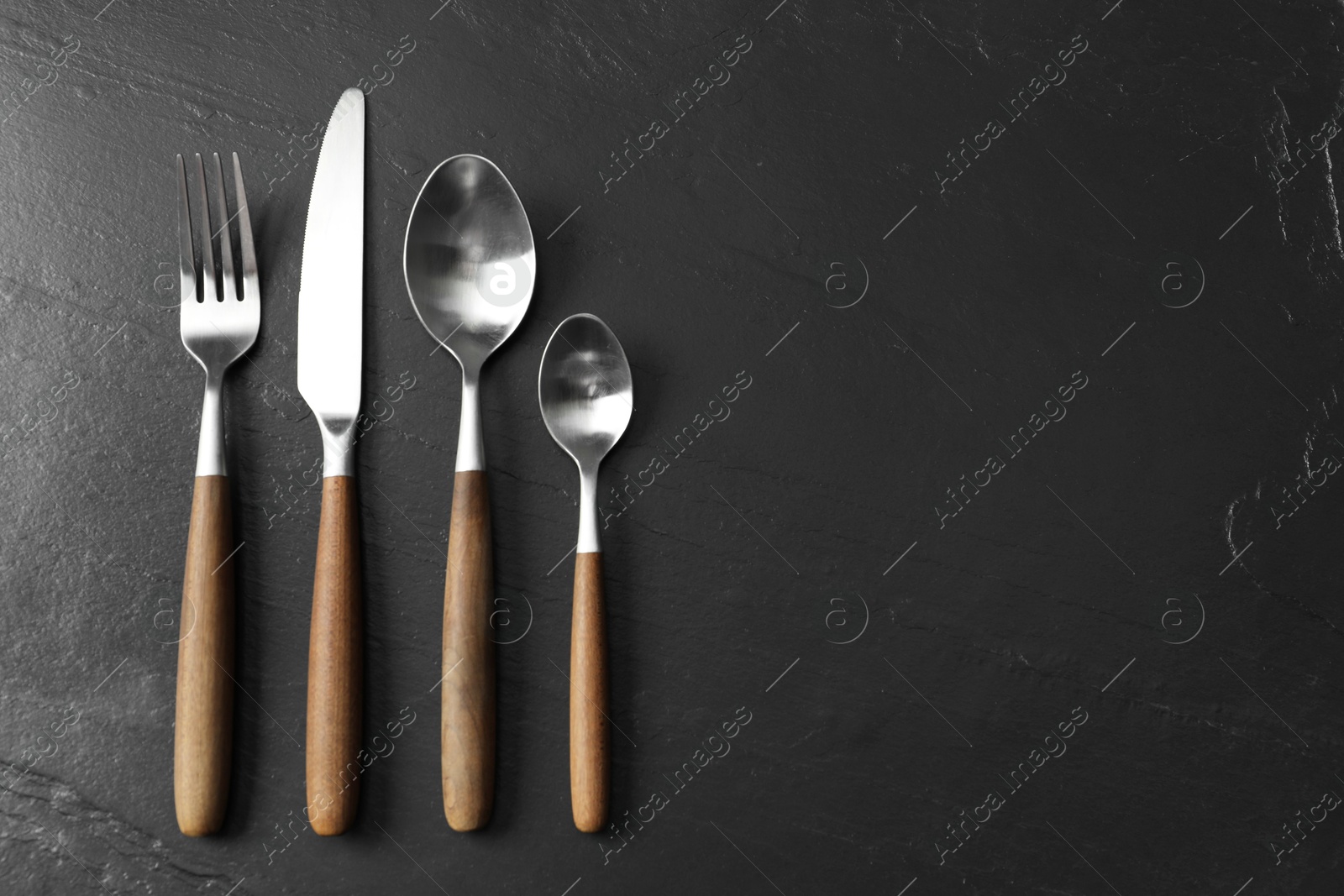 Photo of Stylish cutlery on black table, flat lay. Space for text