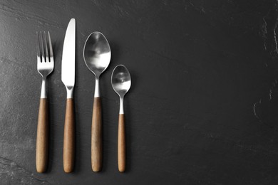 Photo of Stylish cutlery on black table, flat lay. Space for text