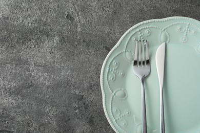 Photo of Stylish silver cutlery and plate on grey table, top view. Space for text