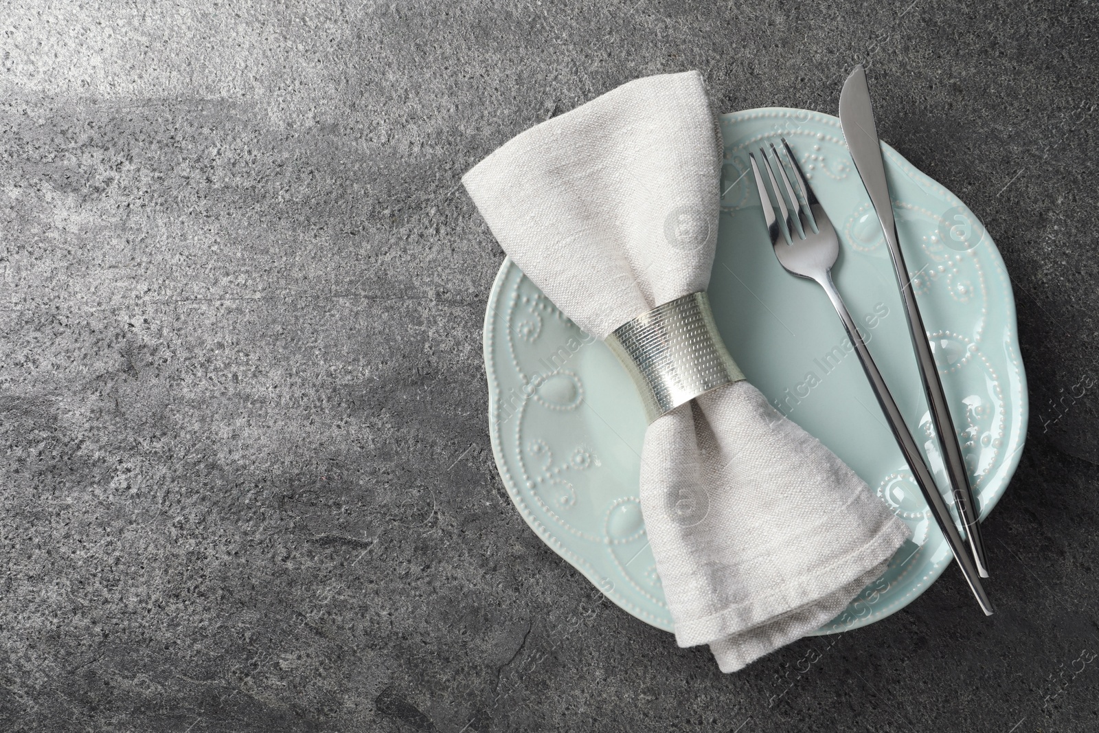 Photo of Stylish silver cutlery, plate and napkin on grey table, top view. Space for text