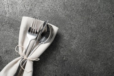 Photo of Stylish silver cutlery and napkin on grey table, top view. Space for text