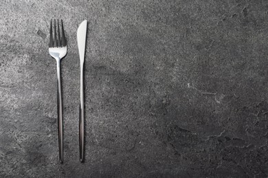 Photo of Stylish silver cutlery on grey table, top view. Space for text