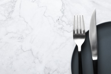 Photo of Stylish cutlery and plate on white marble table, top view. Space for text