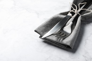 Stylish cutlery and napkin on white marble table, space for text