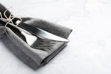 Photo of Stylish cutlery and napkin on white marble table, space for text