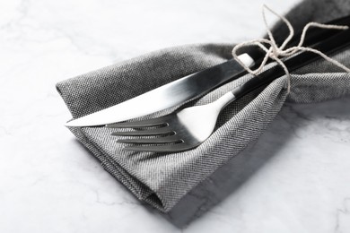 Photo of Stylish cutlery and napkin on white marble table, closeup