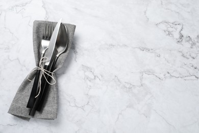 Photo of Stylish cutlery and napkin on white marble table, top view. Space for text