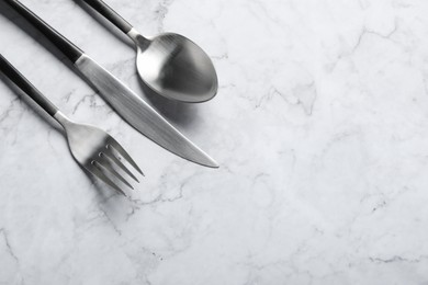 Photo of Stylish cutlery on white marble table, flat lay. Space for text