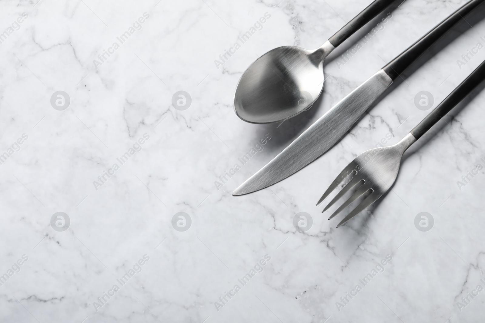 Photo of Stylish cutlery on white marble table, flat lay. Space for text