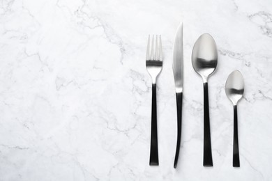 Photo of Stylish cutlery on white marble table, flat lay. Space for text