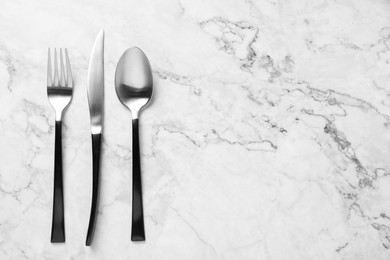 Photo of Stylish cutlery on white marble table, flat lay. Space for text