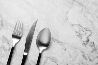 Photo of Stylish cutlery on white marble table, flat lay. Space for text