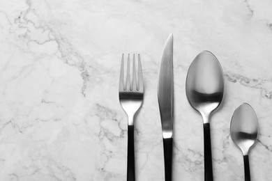 Photo of Stylish cutlery on white marble table, flat lay. Space for text