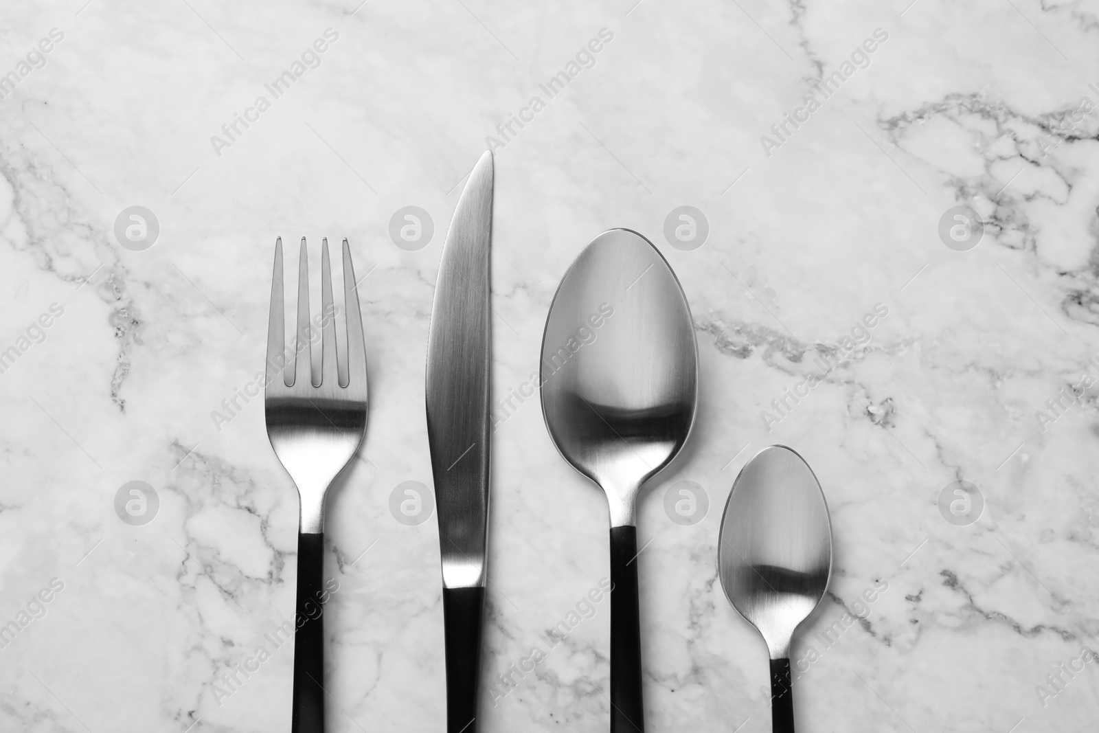 Photo of Stylish cutlery on white marble table, flat lay