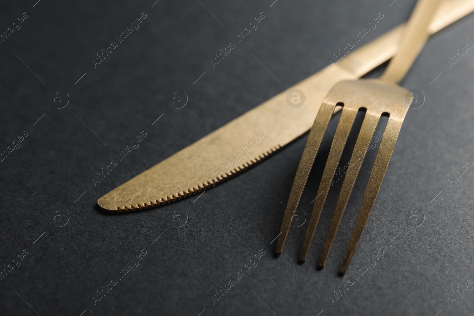 Photo of Elegant golden cutlery on black background, closeup