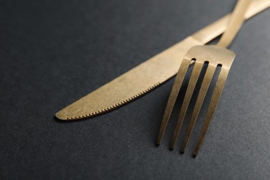 Photo of Elegant golden cutlery on black background, closeup