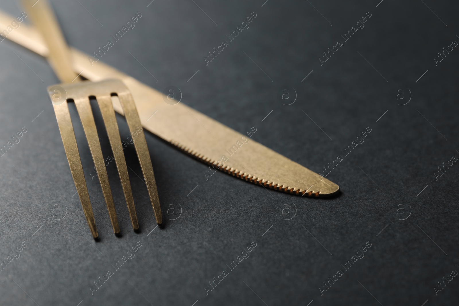 Photo of Elegant golden cutlery on black background, closeup