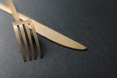 Photo of Elegant golden cutlery on black background, closeup