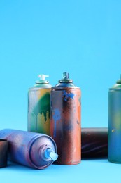 Photo of Many spray paint cans and caps on light blue background