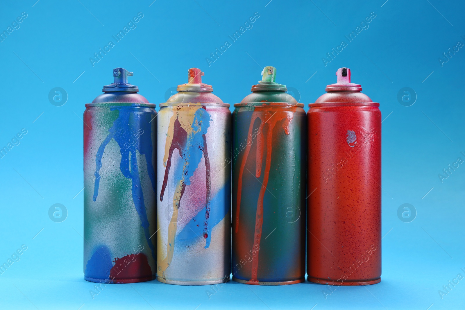 Photo of Many spray paint cans on light blue background