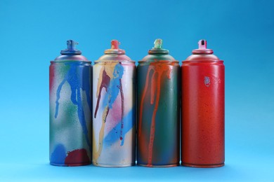 Photo of Many spray paint cans on light blue background