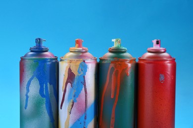 Photo of Many spray paint cans on light blue background