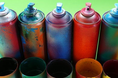 Photo of Many spray paint cans with caps on green background