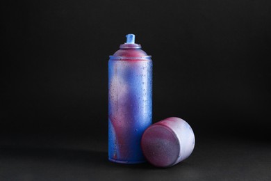 Photo of One spray paint can with cap on dark background