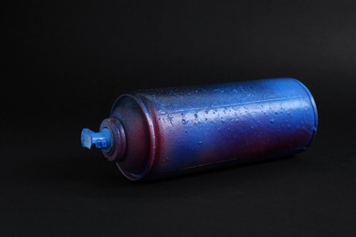 Photo of One spray paint can on dark background, closeup