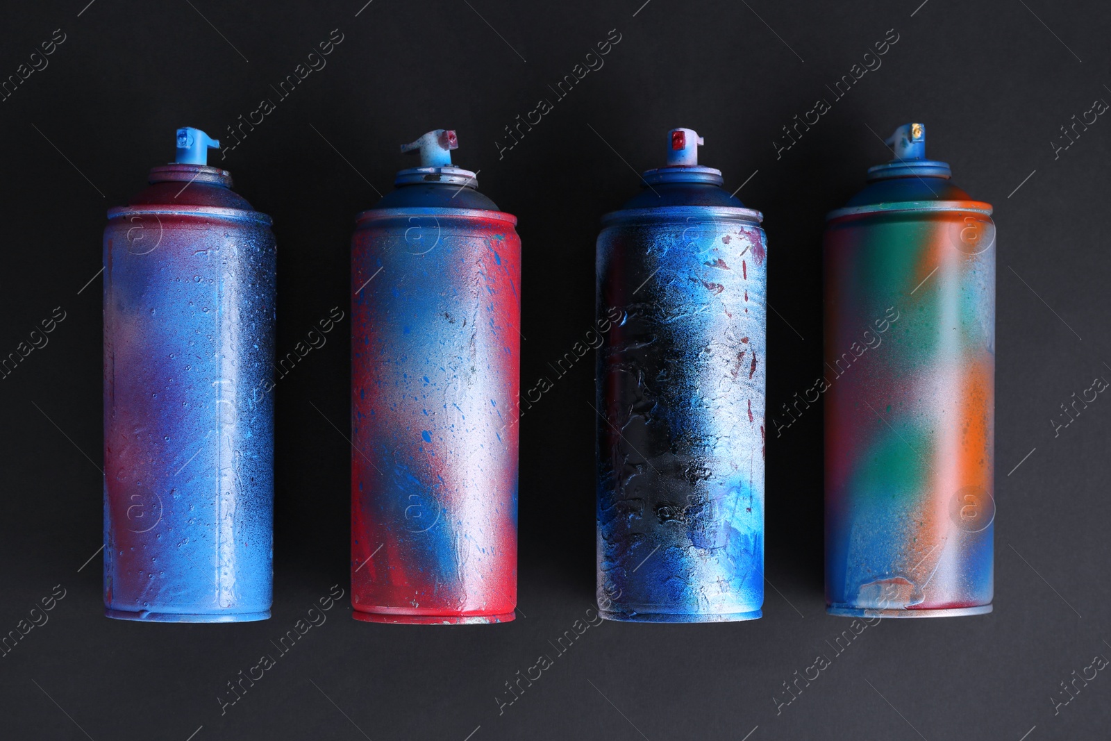 Photo of Many spray paint cans on dark background, flat lay