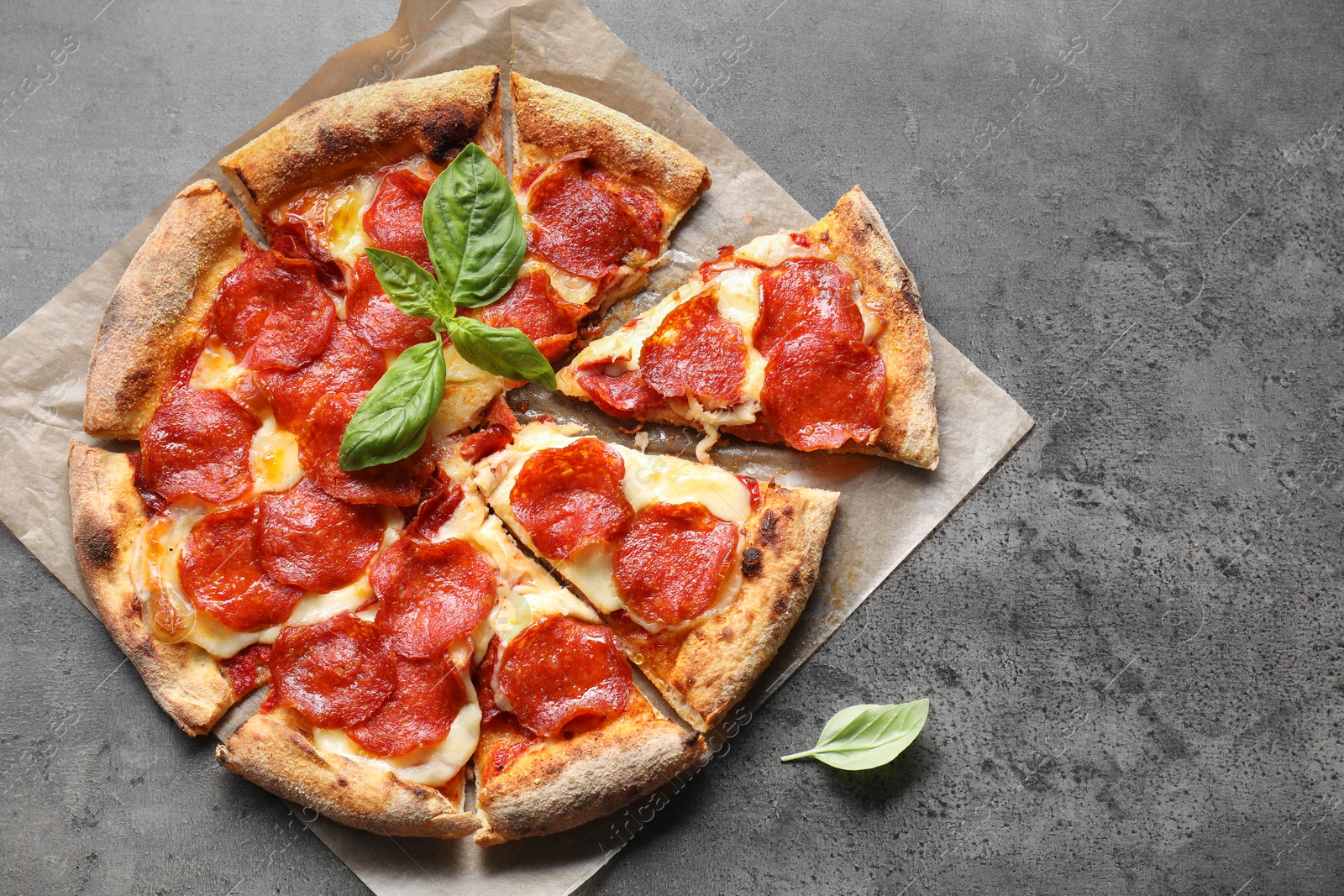 Photo of Tasty pepperoni pizza with basil on grey table, top view. Space for text