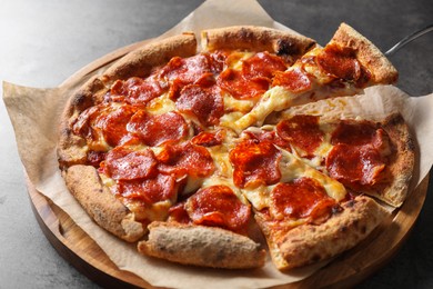 Photo of Taking piece of tasty pepperoni pizza at grey table, closeup