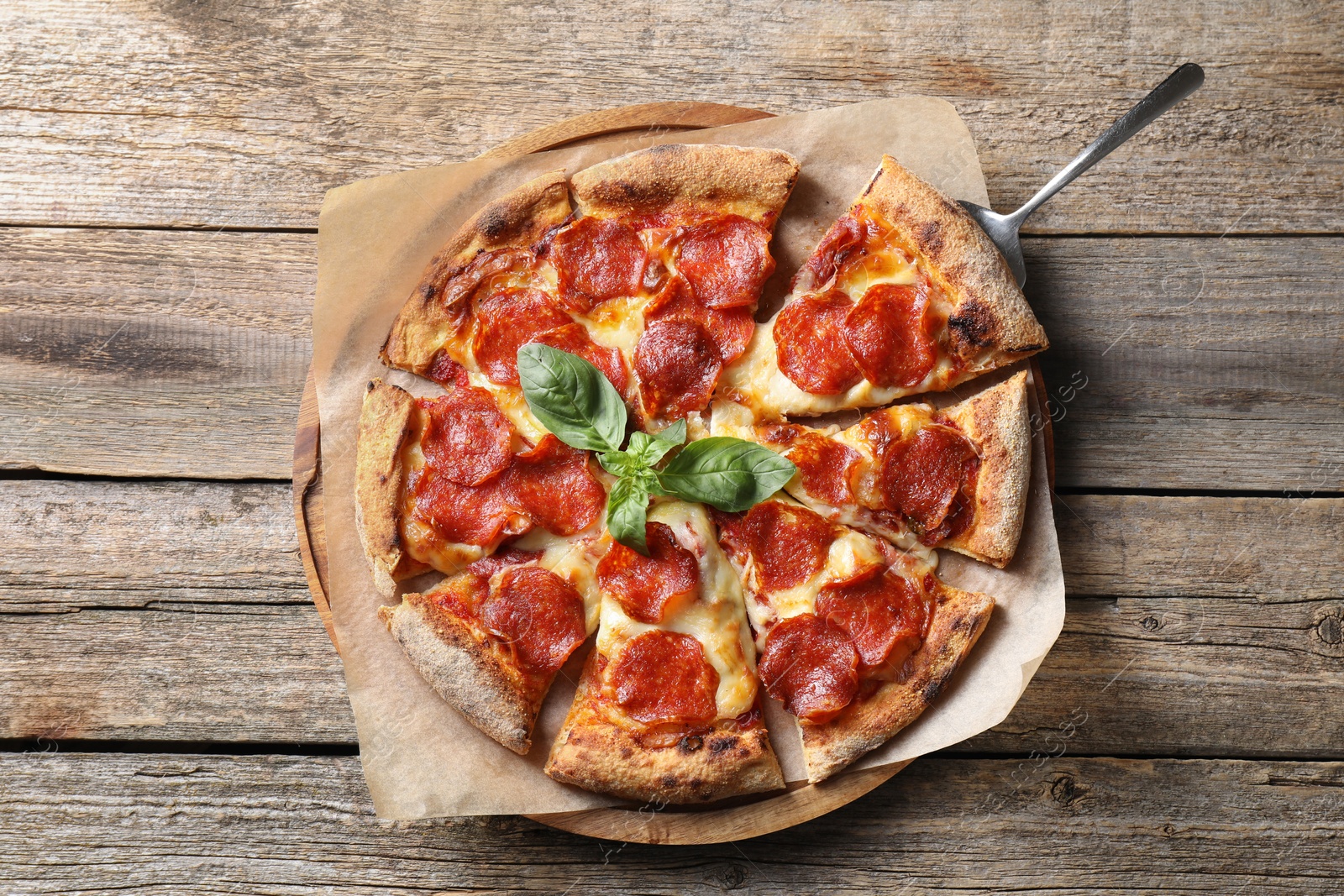 Photo of Tasty pepperoni pizza with basil on wooden table, top view