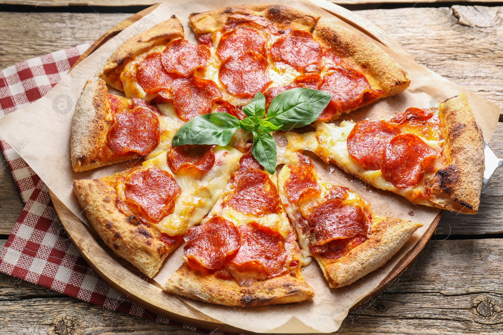 Photo of Tasty pepperoni pizza with basil on wooden table, above view