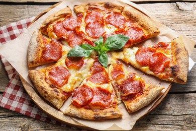 Photo of Tasty pepperoni pizza with basil on wooden table, above view