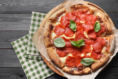 Photo of Tasty pepperoni pizza with basil on black wooden table, top view