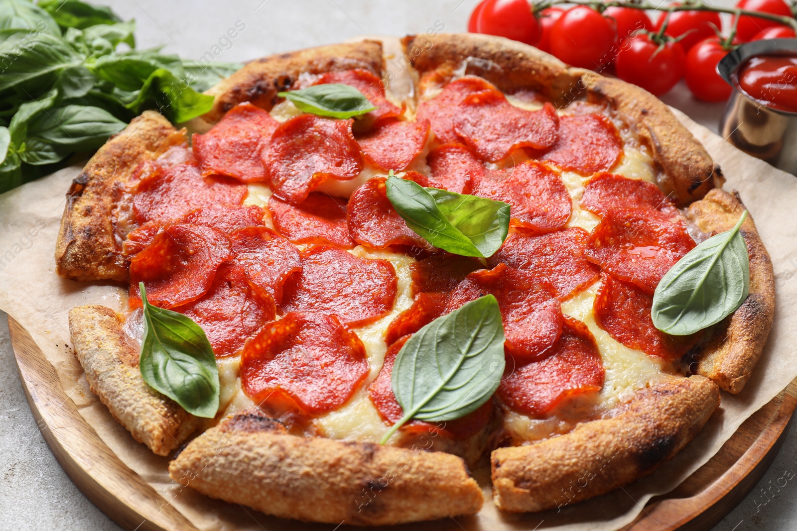 Photo of Tasty pepperoni pizza with basil and tomatoes on table