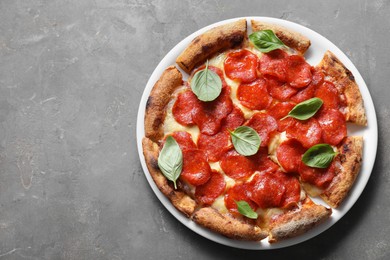 Photo of Tasty pepperoni pizza with basil on grey table, top view. Space for text