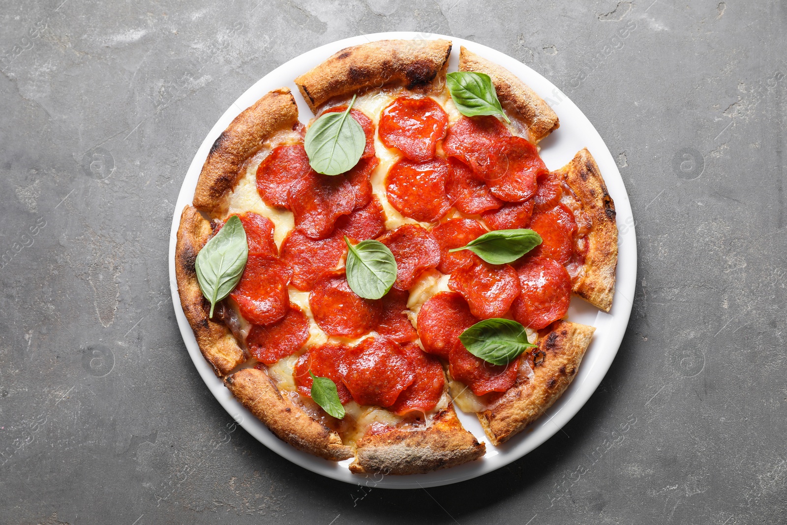 Photo of Tasty pepperoni pizza with basil on grey table, top view