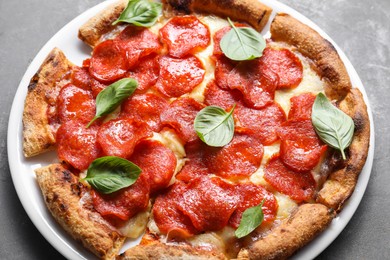 Tasty pepperoni pizza with basil on grey table, above view